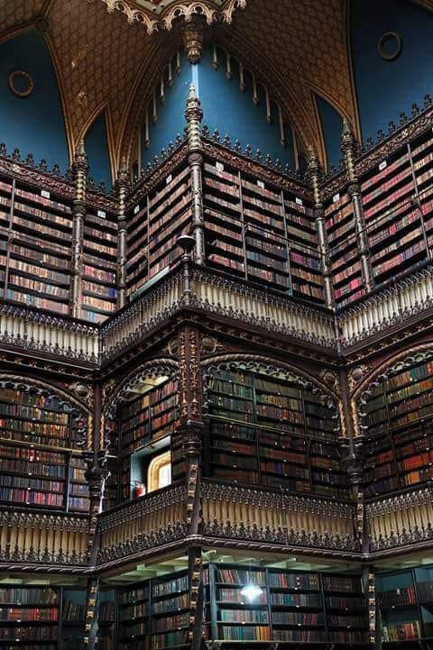 Interior of the Real Gabinete Português de Leitura, a 19th-century library in Rio de Janeiro, with tiered wooden shelving rising toward a stained-glass skylight
